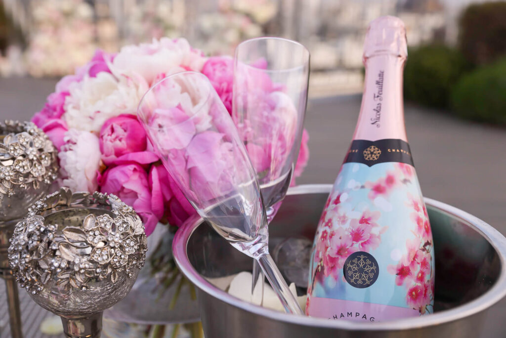 Champagne ice bucket with Ruinart Champagne, two elegant flutes, and a stunning bouquet of mixed roses and peonies.