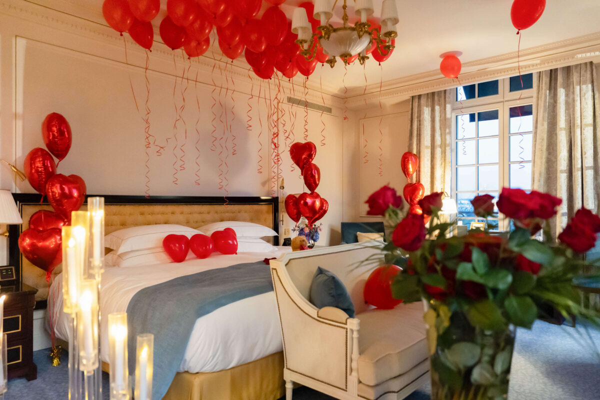 Romantic suite décor at Shangri-La Paris featuring candles, balloons, a heart made of rose petals, and a teddy bear holding a love note, creating a luxurious and intimate post-proposal setting.