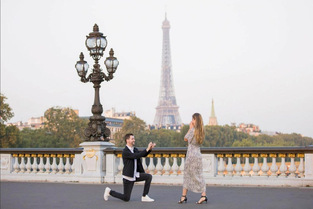 Man proposing on Pont Alexandre III with Eiffel Tower view in the background, luxury engagement location in Paris.