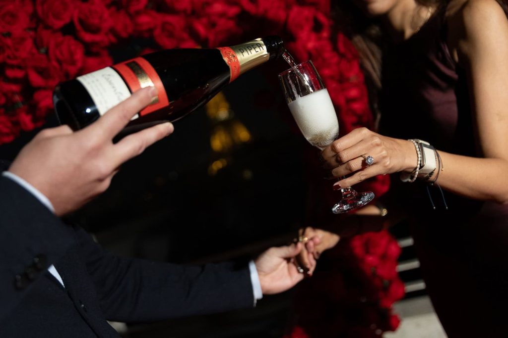 Champagne toast during private rooftop proposal in Paris with Eiffel Tower view and red roses decoration