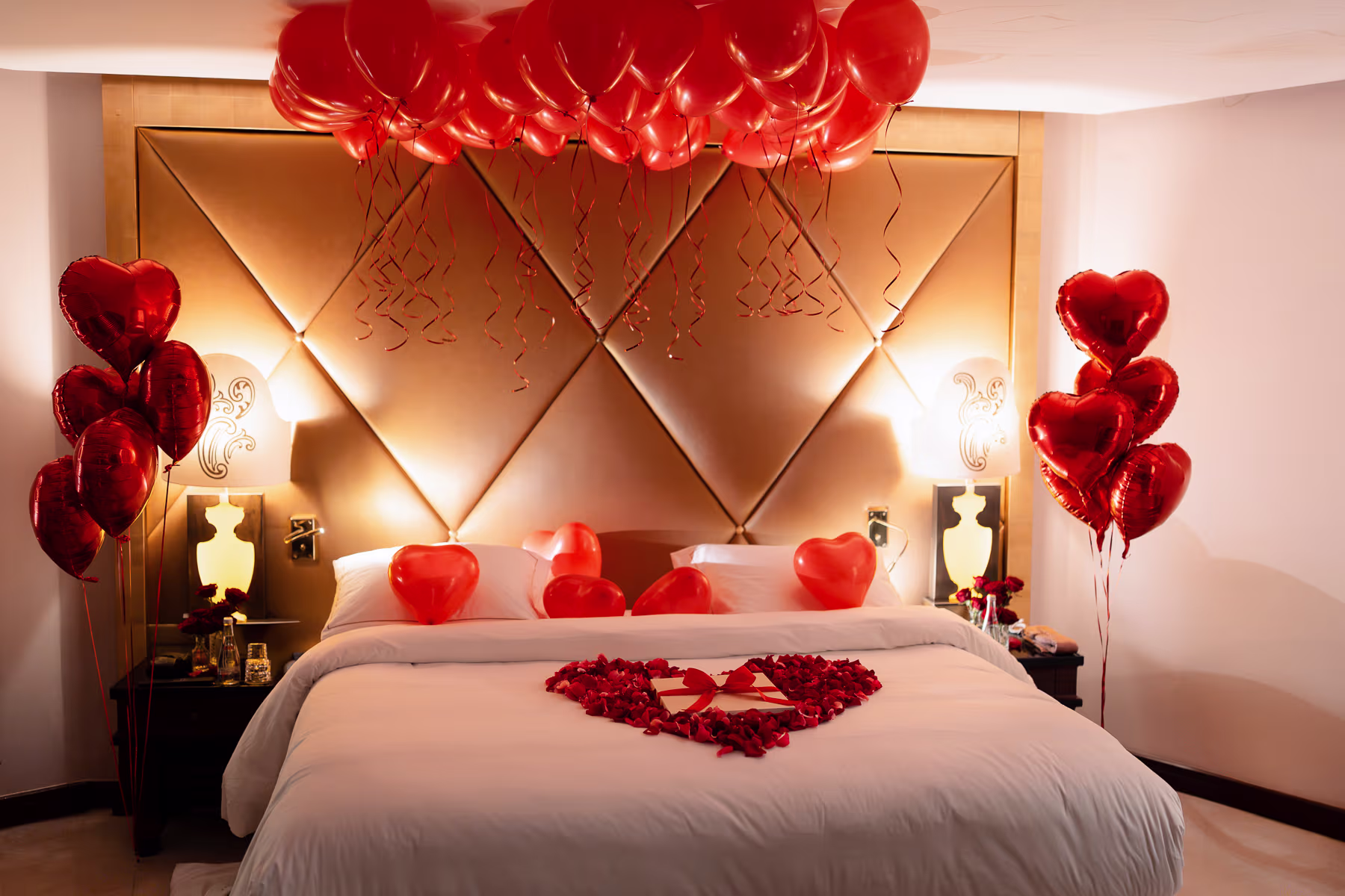 Paris proposal package hotel room decoration with red heart balloons, rose petal heart and champagne