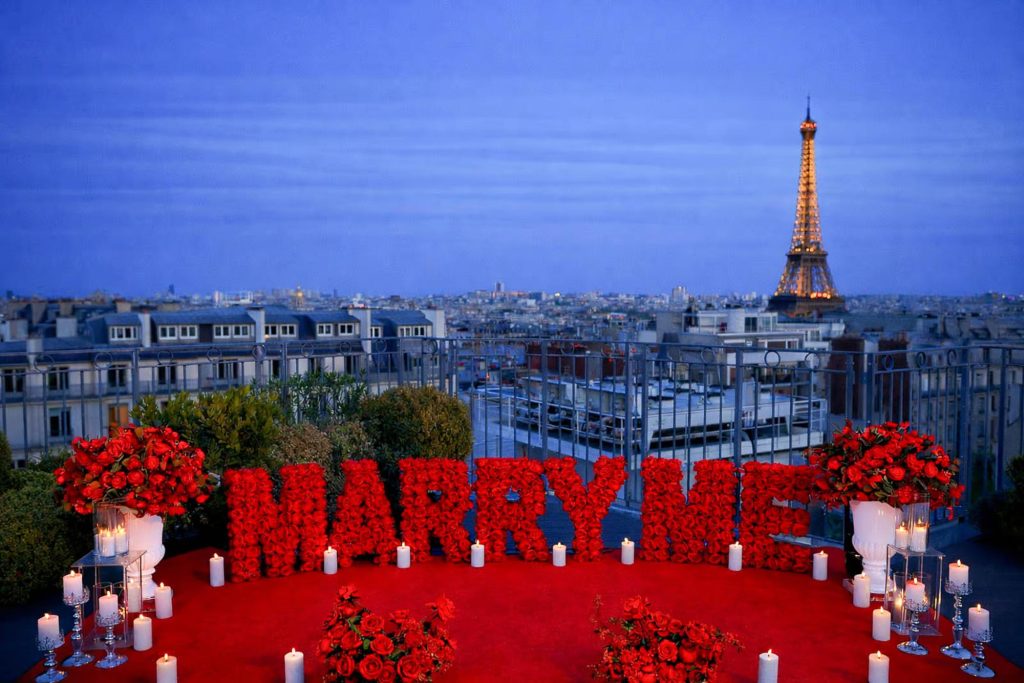 Decoración para una propuesta de matrimonio con las letras «Red Marry Me» en la azotea del Copernic, con las luces de la Torre Eiffel de París