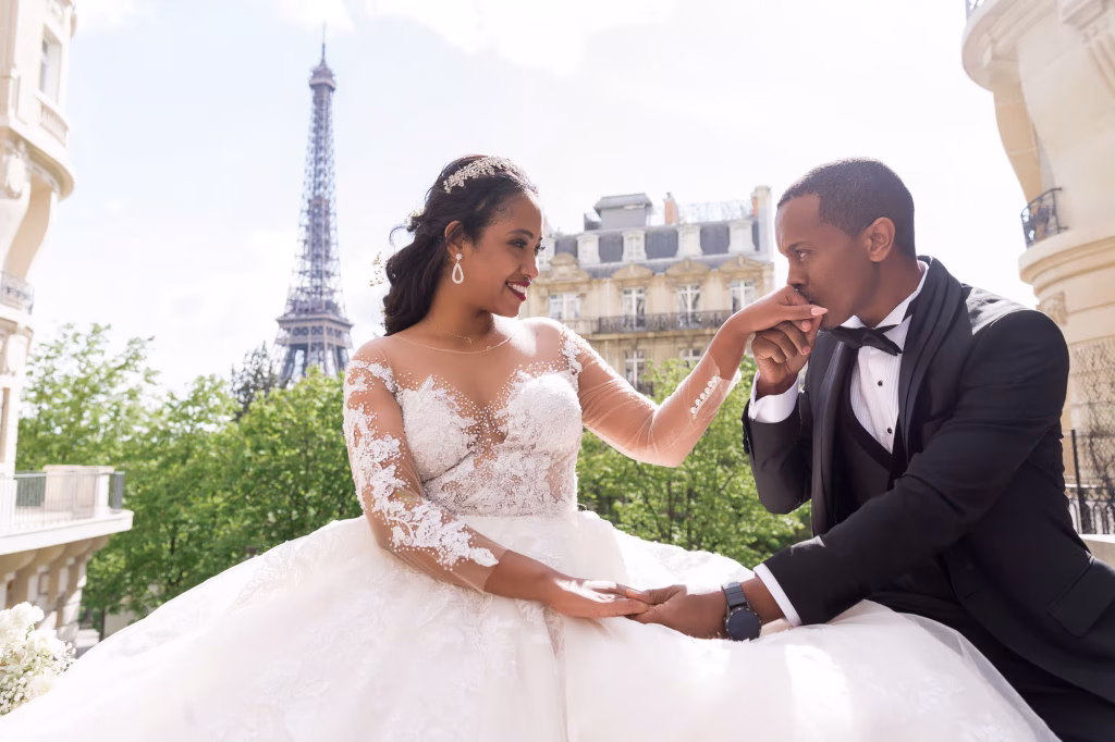 Les mariés lors d'une fugue amoureuse de luxe sur l'avenue de Camoëns à Paris, avec la Tour Eiffel en arrière-plan.